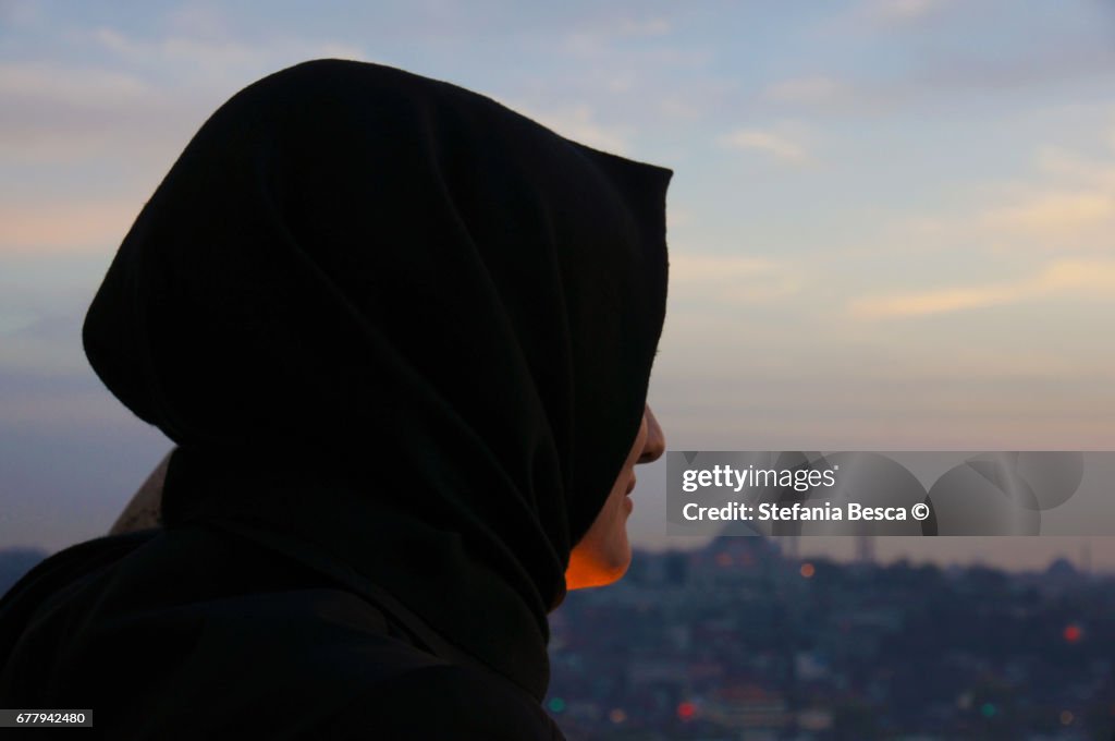 Young woman with veiled head looks at the panorama