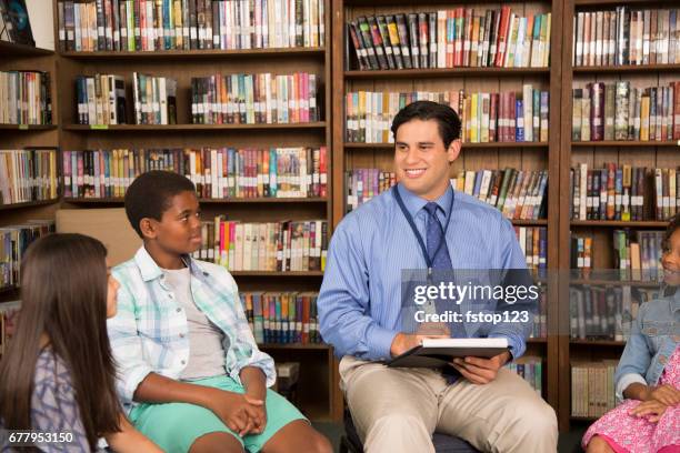 basisschool raadgever met studenten in de bibliotheek. - schoolbegeleider stockfoto's en -beelden