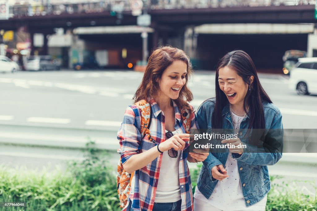Happy women in Tokyo using tablet at the street