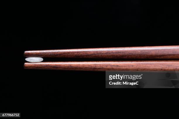 a grain of rice clamped by wood chopsticks - chopsticks stock pictures, royalty-free photos & images