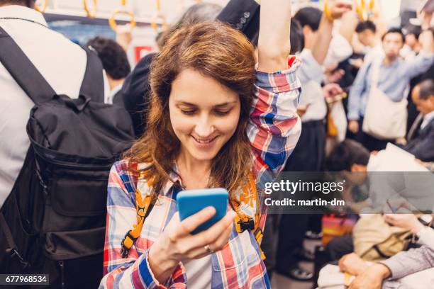 地下鉄で携帯電話を使用して笑顔の女性 - 通勤電車 ストックフォトと画像