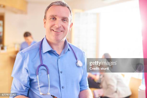 smiling doctor in his surgery - shirt stock pictures, royalty-free photos & images
