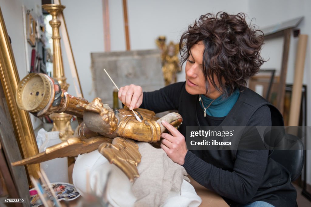 Restaurateur en framer laboratorium craftswomen: Restoring antieke Gouden Engel standbeeld