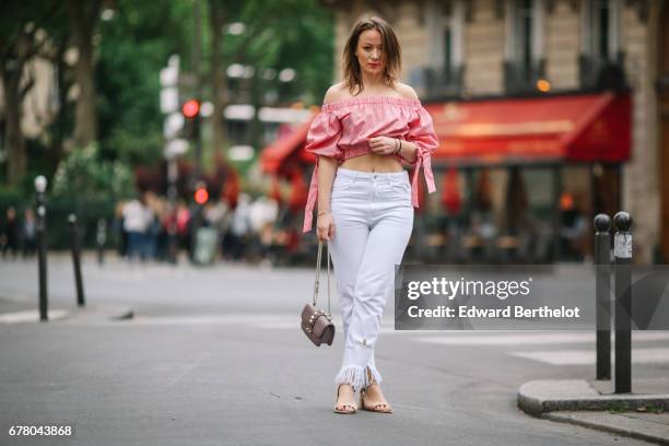 Amelie Lloyd, fashion blogger, wears a Valentino rockstud bag, Zara ripped white jeans, a Zara red and white off shoulder bare belly top, and Zara...