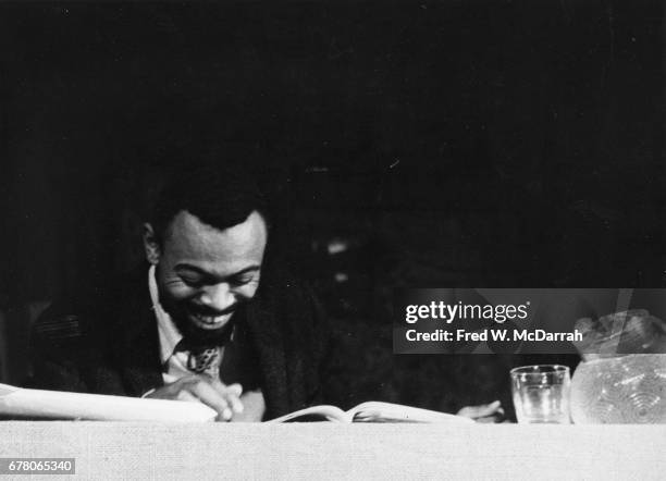 American poet and playwright LeRoi Jones laughs as he sits at a table during a benefit for Yugen Press at the Living Theatre , New York, New York,...