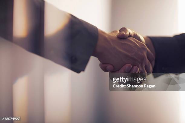 handshake in contemporary office space - alianza fotografías e imágenes de stock