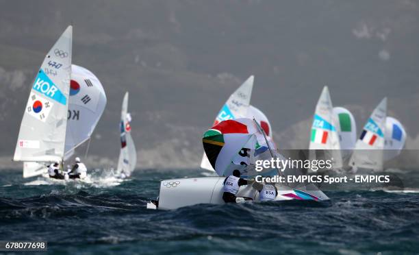 South Africa's 470 crew Jim Asenathi and Roger Hudson right their dinghy as the fleet sails on during the first day of their Olympic campaign off...