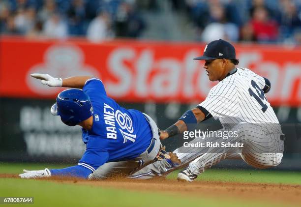 Darwin Barney of the Toronto Blue Jays slides safely into second base for a double before the tag of Starlin Castro of the New York Yankees in the...