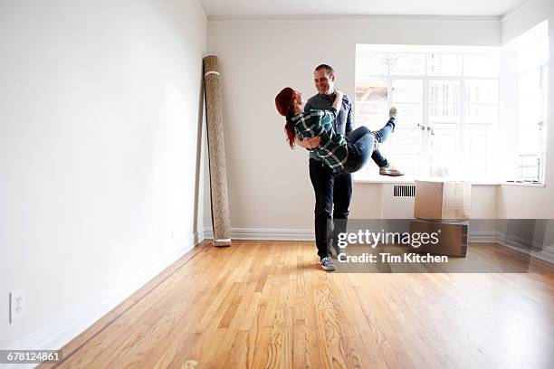man lifting woman in empty apartment - mover stockfoto's en -beelden