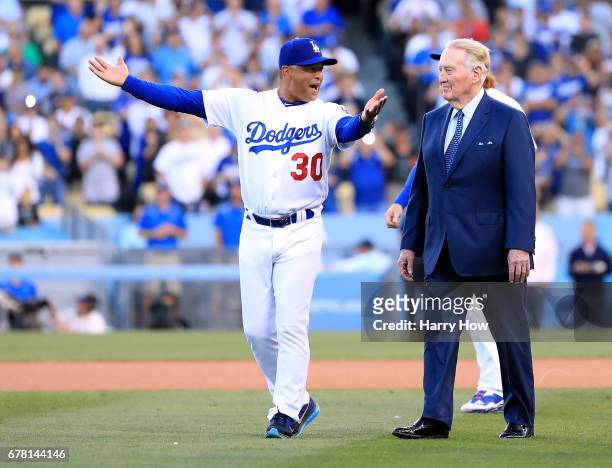 Los Angeles Dodgers manager Dave Roberts laughs as he leads announcer Vin Scully to the field during his induction into the Los Angeles Dodgers Ring...