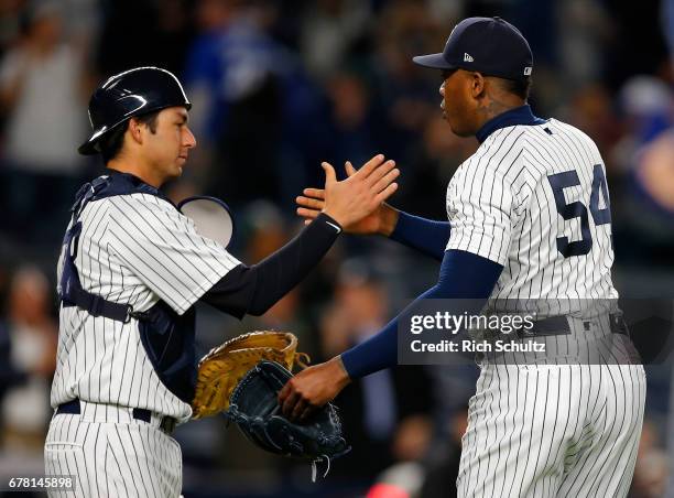 Catcher Kyle Higashioka and closer Aroldis Chapman of the New York Yankees congratulate each other after defeating the Toronto Blue Jays 8-6 in a...