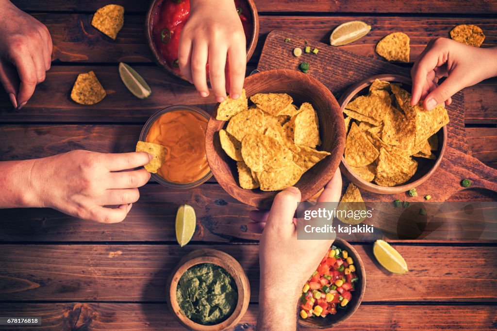 Familie essen Nachos mit Saucen