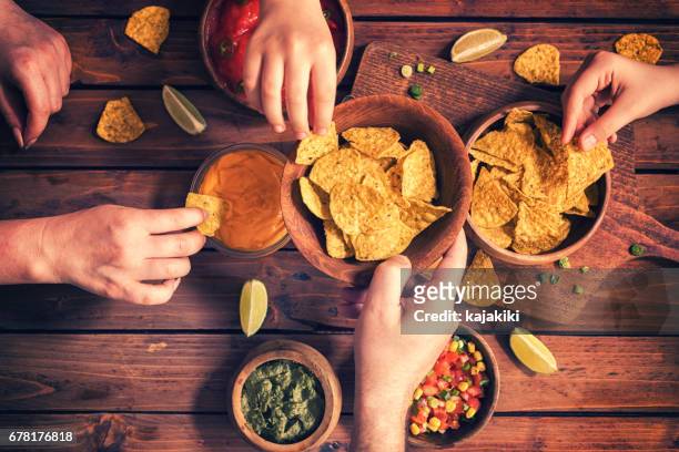 familie eten nachos met sauzen - hands share stockfoto's en -beelden