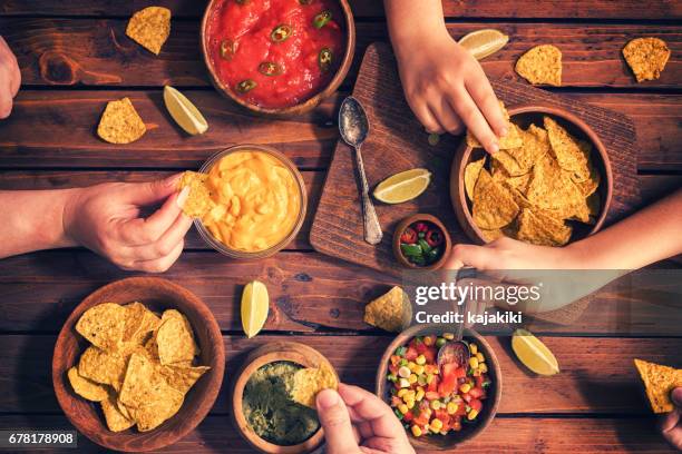 family eating nachos with sauces - family eating potato chips stock pictures, royalty-free photos & images