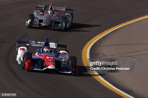 Carlos Munoz of Colombia, driver of the A.J. Foyt Enterprises Chevrolet and Will Power of Australia, driver of the Team Penske Chevrolet drive during...