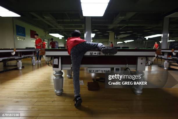 This photo taken on May 2, 2017 shows 13-year-old student Ma Hailong stretching to play a shot at the World Snooker College in Beijing. At the World...