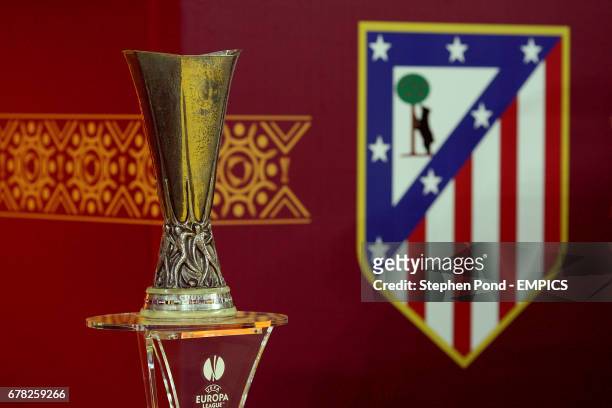The UEFA Europa League trophy stands next to an Atletico Madrid club badge