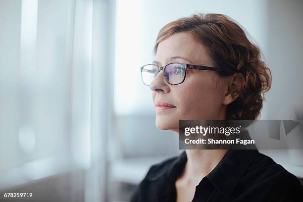 businesswoman looking ahead in business office - older woman with brown hair foto e immagini stock