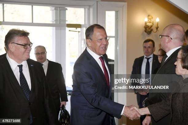 Russian Foreign Minister Sergei Lavrov shakes hands with delegation members as his Finnish counterpart Timo Soini looks on during their meeting at...