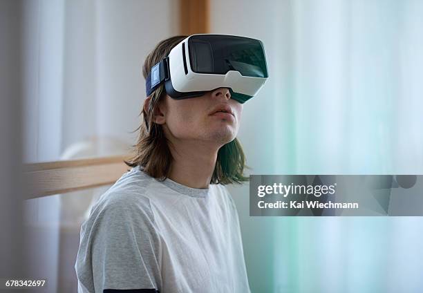 man viewing virtual content with vr mask at ho - 3d glasses stock pictures, royalty-free photos & images