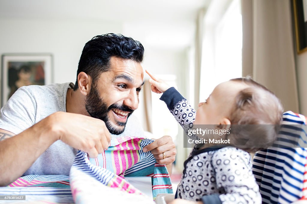 Happy father playing with baby girl at home