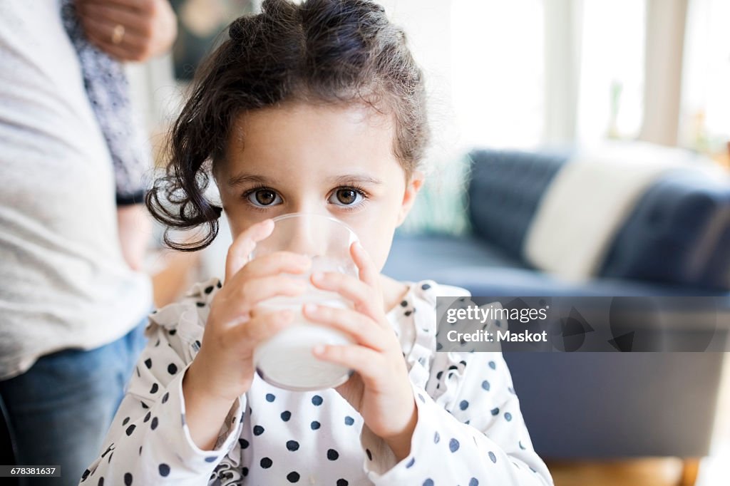 Portrait of girl drinking milk while father standing in background