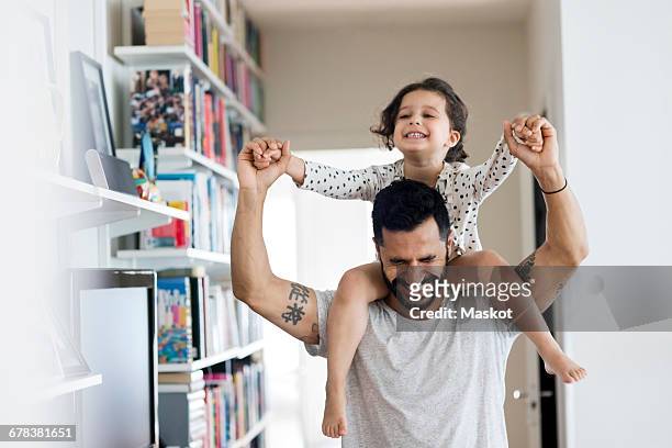 happy father carrying girl on shoulder while standing at home - father foto e immagini stock