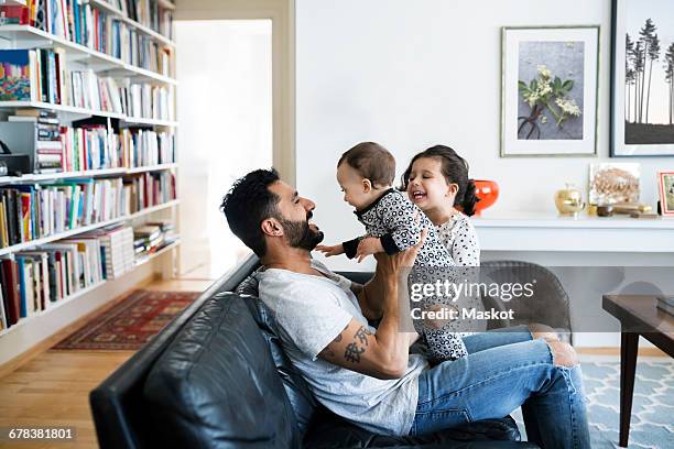 father and daughter playing with baby girl on sofa at home - arab family happy photos et images de collection