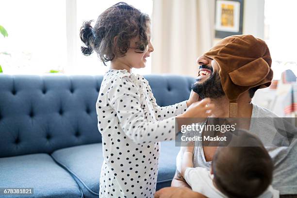 happy father wearing cap playing with children in living room - bébé rire photos et images de collection