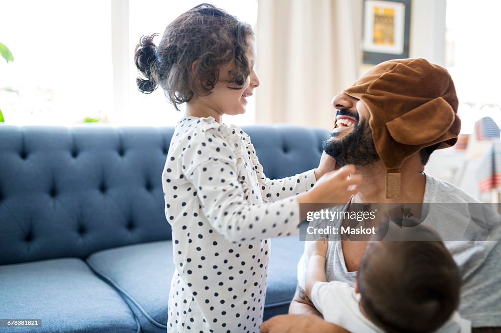 Happy father wearing cap playing with children in living room