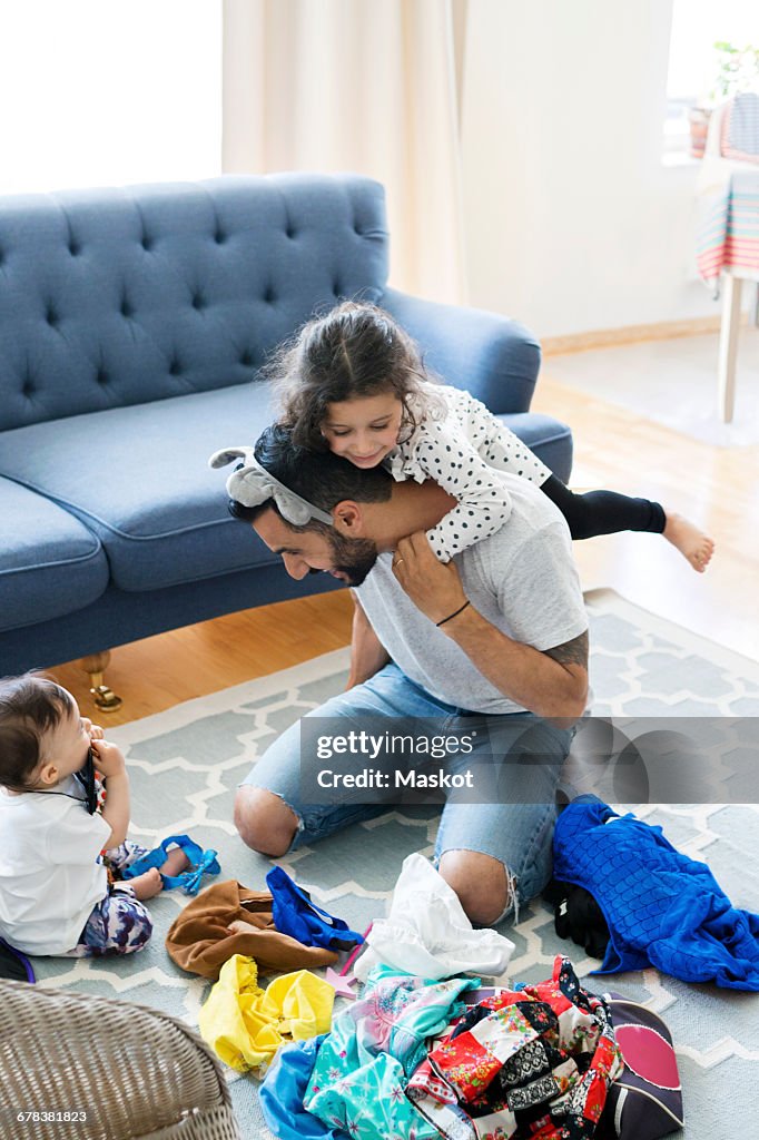 High angle view of father playing with daughters on carpet at home