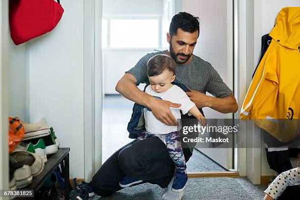 father dressing daughter while crouching at doorway - rock bildbanksfoton och bilder