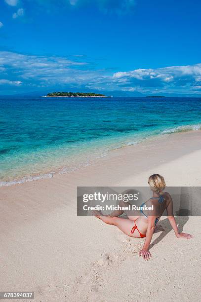 woman sitting on a the white sand beach of beachcomber island, mamanucas islands, fiji, south pacific, pacific - beachcomber island stock pictures, royalty-free photos & images