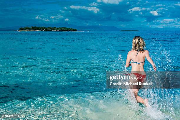 woman running in the water, beachcomber island, mamanucas islands, fiji, south pacific, pacific - beachcomber island stock pictures, royalty-free photos & images