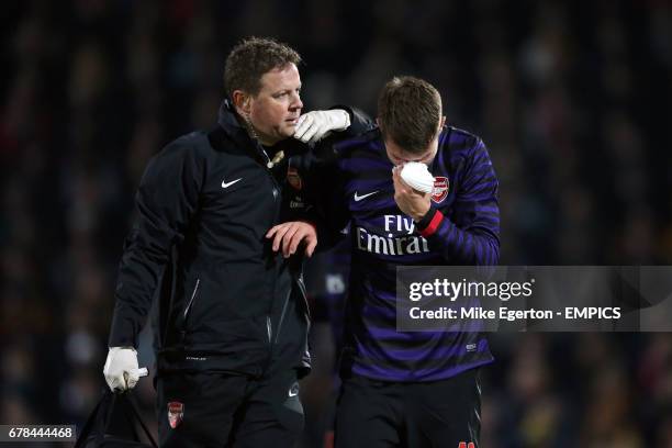 Arsenal's Aaron Ramsey is led off with a facial injury by physio Colin Lewin