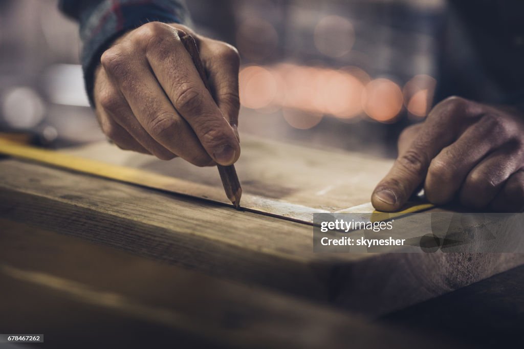 Close up of unrecognizable carpenter drawing measurements on a wood.