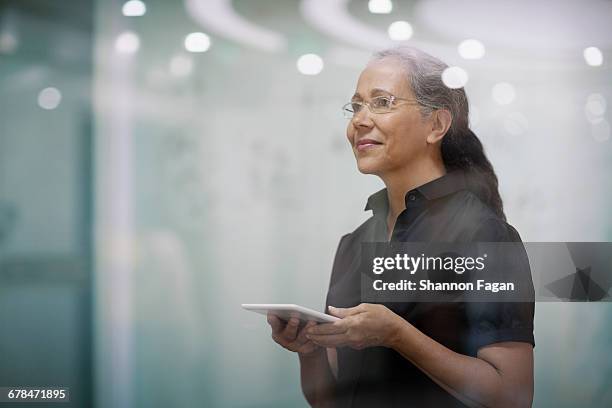 senior woman with smart tablet computer in office - red blouse fotografías e imágenes de stock