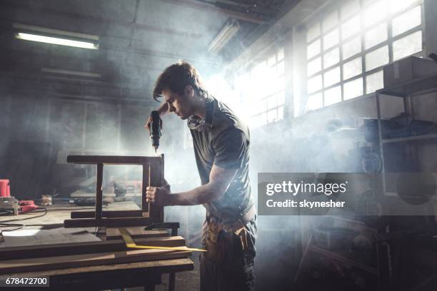 carpenter mâle à l’aide de forage à une chaise dans un atelier de réparation. - menuisier photos et images de collection