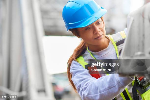 vrouwelijke ingenieur uitvoeren van reparaties aan de brug - safety harness stockfoto's en -beelden