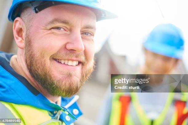 male engineer smiles to camera - industrial building site stock pictures, royalty-free photos & images