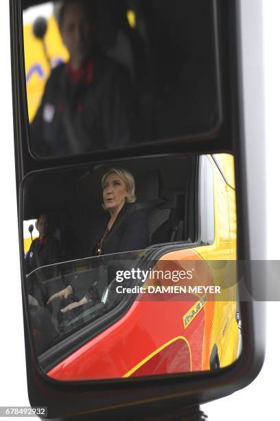 French presidential election candidate for the far-right Front National party, Marine Le Pen is reflected in the wing mirror of a lorry as she sits...