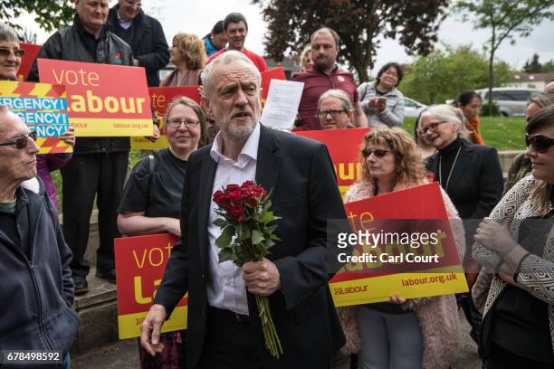 Labour Party leader Jeremy Corbyn holds red roses given to him by activists and supporters as he visits a local shopping arcade on May 4, 2017 in...