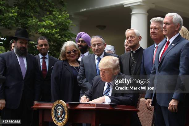 President Donald Trump is flanked by clergy members as he signs an Executive Order on Promoting Free Speech and Religious Liberty, during a National...