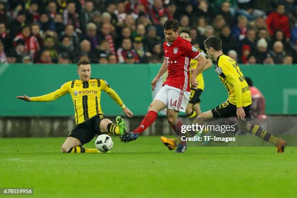 Julian Weigl of Dortmund , Marco Reus of Dortmund and Xabi Alonso of Bayern Munich battle for the ball during the German Cup semi final soccer match...