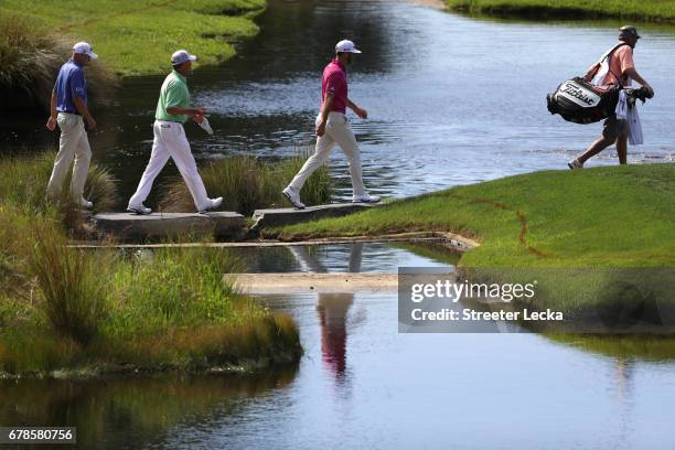 Dustin Johnson, Davis Love III, and Bill Haas walk on the 17th hole during round one of the Wells Fargo Championship at Eagle Point Golf Club on May...