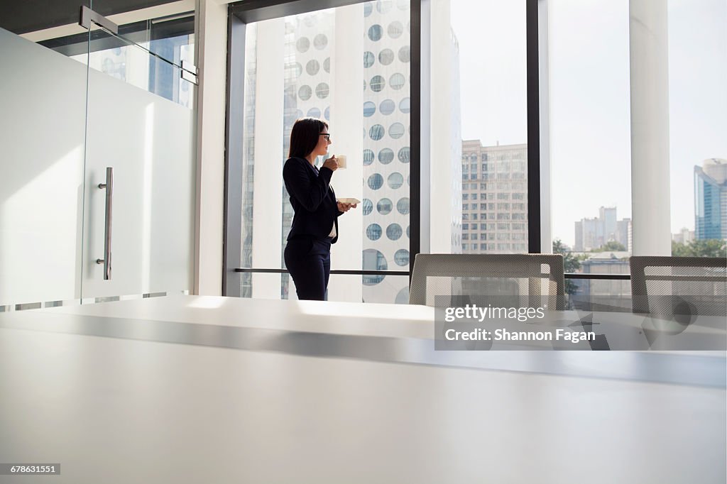 Businesswoman with coffee and looking out window