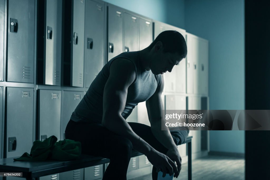 Mann sitzt auf der Bank im Umkleideraum nach dem Training im Fitness-Studio