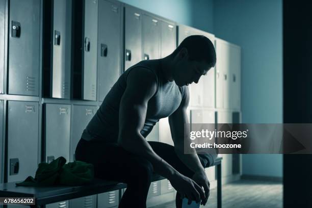 hombre sentado en la banca en vestidor después de hacer ejercicio en el gimnasio - vestuario fotografías e imágenes de stock