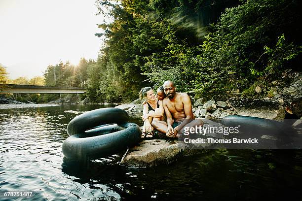 family sitting together on rock in river - budding tween stock pictures, royalty-free photos & images