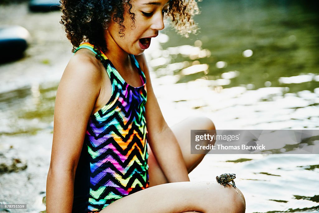 Surprised girl with frog perched on her knee